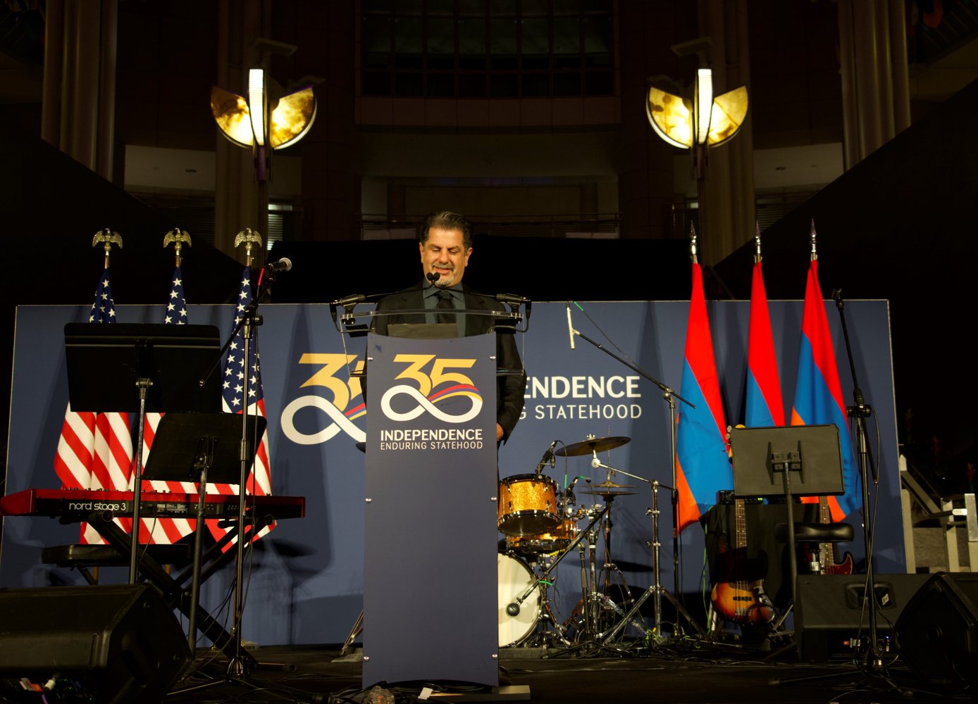 Rev speaking at the Armenian independence celebration, with American and Armenian flags behind him